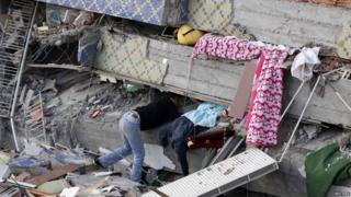 A man searches for his family in rubble
