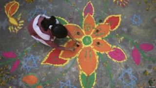 Girl painting a rangoli with different coloured powders