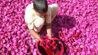Boy dipping diyas into paint