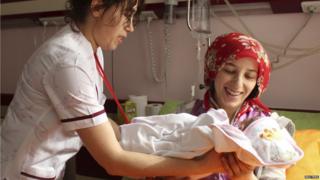 Azra is handed to her mother, Semiha.