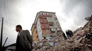 People stare at the ruins of people's homes.