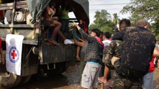 Military personnel help to evacuate a village near Iligan City, Philippines, 17 December 2011