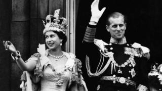 Queen Elizabeth II and her husband Prince Phillip waving to crowds from the balcony of Buckingham Palace.
