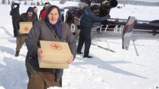Bosnian people carrying food supplies in a remote village