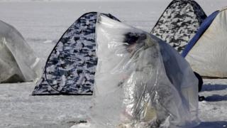 Ukrainian man fishing through an ice hole on the Dnipro river