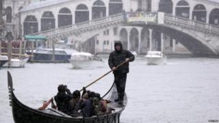 A gondolier takes passengers across the Grand Canal in Venice, Italy