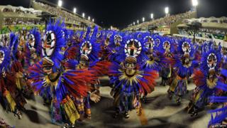 A dance group dressed in purple and orange take part in the opening night of the Rio carnival.