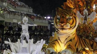 A man dances on a platform next to a tiger float on the opening night of the Rio carnival.