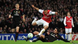 Arsenal's Theo Walcott being tackled by AC Milan's midfielder Alberto Aquilani