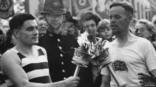 Veteran runner H J Bignall (right) hands over the Olympic torch to Fred Prevett at Redhill, Surrey, during the flame's journey from Dover to Wembley Stadium, London, for the opening of the 1948 London Olympics.