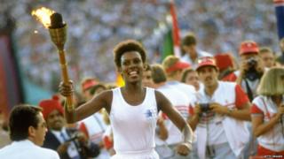 Gina Hemphill runs through the stadium with the Olympic Torch before the 1984 Olympic Games at the Coliseum Stadium in Los Angeles, USA