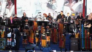 Commonwealth choir performing outside Buckingham Palace surrounded by musicians including Gary Barlow and Lord Llloyd Webber