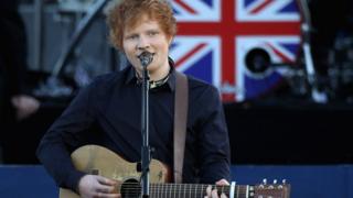 Ed Sheeran performing on stage in front of Buckingham Palace