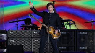 Sir Paul McCartney performing on stage in front of Buckingham Palace