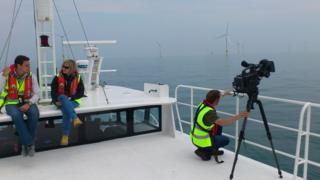 Joe on a boat talking to an expert about wind farms