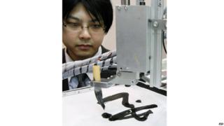 A scientist looks at a robotic paint brush
