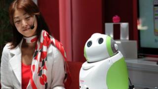 A woman smiles at a robot