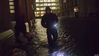 Security guard walks through flood water in the financial district in New York.