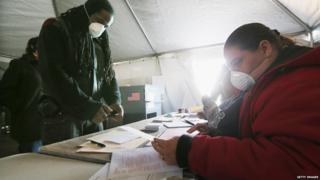 Rockaway resident Jesse James (left) prepares to vote in a makeshift tent set up in the Queens borough of New York City