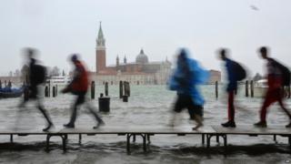 Tourists walk on footbridges during a "acqua alta" on November 11, 2012 in Venice. Rain and wind hit the north of Italy on Sunday and the flooding reached 150 centimetres in Venice.