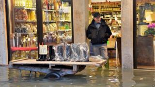 A shoes seller displays wellies outside his shop in a flooded street during a "acqua alta" on November 11, 2012 in Venice.