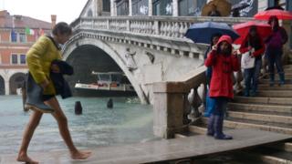 Tourists walk on footbridges near the Rialto bridge during a "acqua alta" on November 11, 2012 in Venice. Rain and wind hit the north of Italy on Sunday and the flooding reached 150 centimetres in Venice.