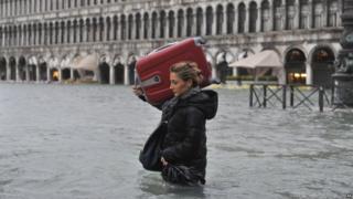 A tourist crosses flooded St. Mark's Square in Venice, Italy, Sunday.