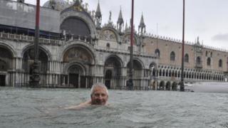 A man enjoys swimming in flooded St. Mark's Square in Venice, Italy.