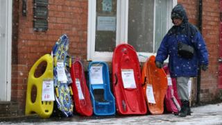 A woman walks past a selection of sledges in Nottinghamshire
