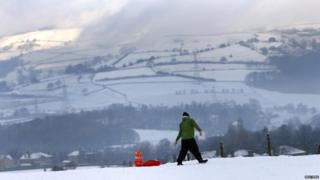 A man pulls a young girl on a sledge through a snow covered field near Halifax