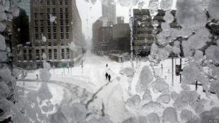 People walk down snow covered streets in Boston.