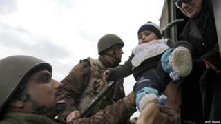 Jordanian soldiers helping refugees out of vehicle
