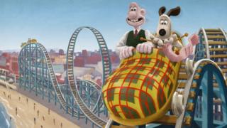 Wallace and Gromit on a rollercoaster at the seaside.