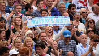Woman holds Murray's Mint banner.