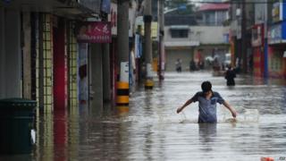 This picture taken on July 9, 2013 shows residents walking along a flooded street in a district in Chengdu, southwest China's Sichuan province.