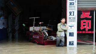 This picture taken on 9 July 2013 shows a man standing in his flooded shop in a district in Chengdu, south-west China's Sichuan province