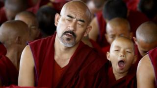 A young Tibetan Buddhist monk yawns