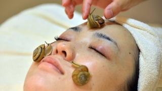 Snails crawl on the face of a woman