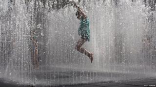Children jump in the fountain on the southbank of the River Thames in London.
