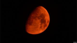 A picture showing a red moon in the night sky.