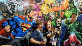 Fans posing in front of a comic mural.