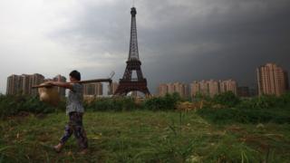 A farmer walks past a replica of the Eiffel Tower in Zhejiang Province, China.