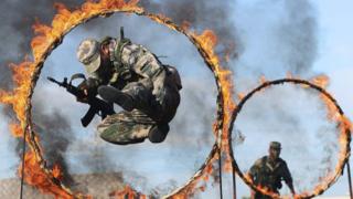 A soldier from the People"s Liberation Army jumps through a ring of fire as part of training during the PLA Army Day in Wenzhou, Zhejiang province.
