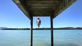 A woman jumps into the water of Lake Forggen in southern Germany.