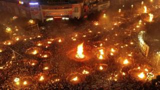 Crowds of people in China from the ethnic Yi minority celebrate with visitors during their Torch Festival in Xichang.