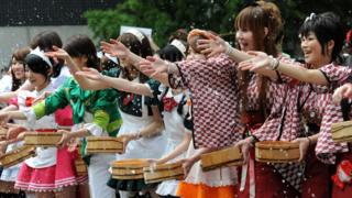 Japanese girls dressed as maids throw water into the air to cool off.
