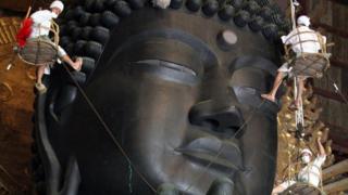 monks clean a Buddha