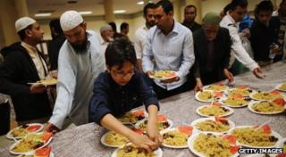 A boy takes a plate of food from a table