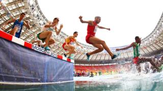 Men racing through water in the Men's 3000 metres steeplechase.