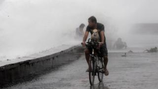 man with dog cycling past waves